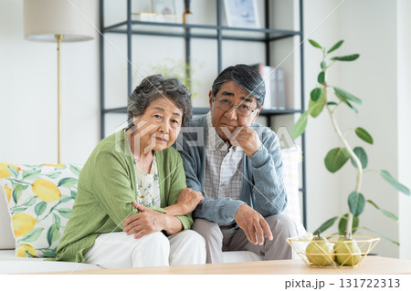 リビングで悩むシニアの夫婦 131722313