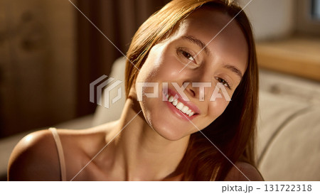 Smiling woman with natural glow in soft morning light 131722318