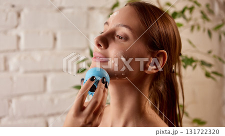 Woman cleansing face with foam brush for gentle skincare routine Woman cleansing face with foam brush for gentle skincare routine 131722320