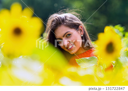 pretty sensual young brunette in a field of sunflowers in a red sweater, happy woman outdoors 131722847