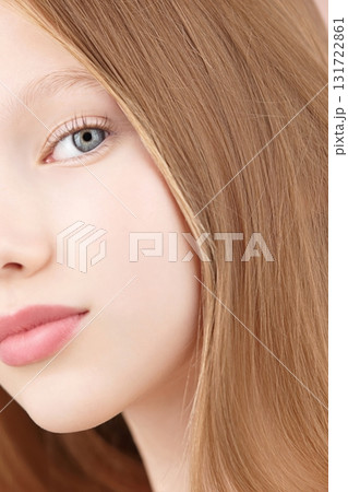 Half face portrait of a funny smiling young girl. Blonde Caucasian girl with blue eyes isolated on pink background. Ads concept skin care for teenagers. Hair care. Copy space. Self care Gen Alpha 131722861