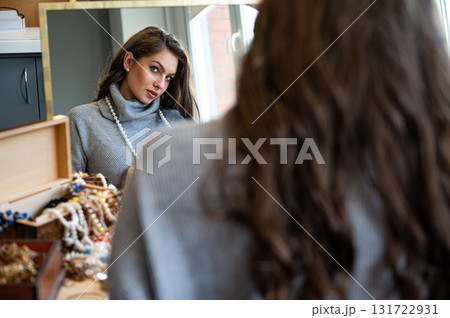 reflection of a woman in mirror choosing and trying different jewelry, soft focus, closeup 131722931