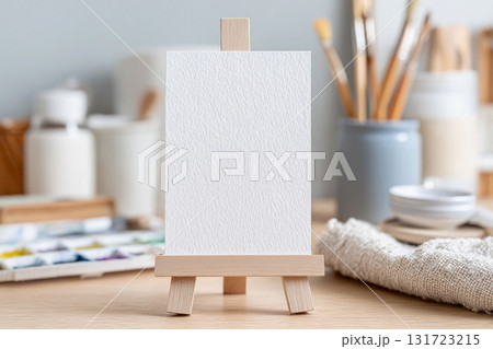 Art studio setup with empty canvas on easel surrounded by supplies for painting and creativity 131723215