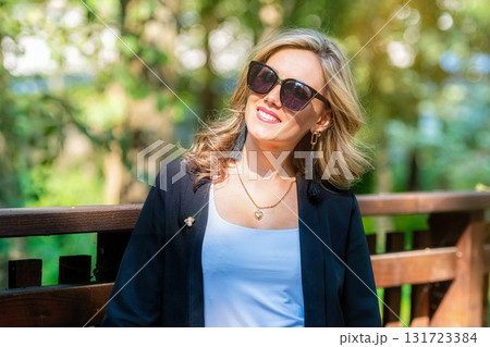fashion portrait of a stylish nice blonde female in sunglasses on a defocused park background fashion portrait of a stylish nice blonde female in sunglasses on a defocused park background 131723384