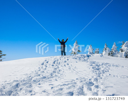 雪山の山頂で両手を広げて万歳するスノーボーダー (長野県、志賀高原、横手山) 131723749