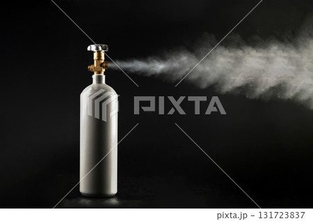 A CO2 gas cylinder with an open valve and gas escaping to the outside on a black background. A CO2 gas cylinder with an open valve and gas escaping to the outside on a black background. 131723837