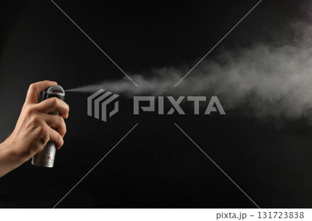 A man sprays pepper spray on a black background, close-up. The concept of self-defense in emergency situations. 131723838