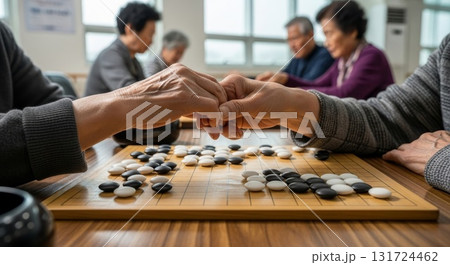 Two elderly asian men shaking hands after traditional go game match with black white stones on wooden board in community center Two elderly asian men shaking hands after traditional go game match with black white stones on wooden board in community center 131724462