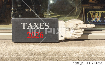 Taxes 2026 new year symbol. Concept words Taxes 2026 on beautiful black wooden hand sign. Beautiful shop display background. Business and taxes 2026 new year concept. Copy space. 131724784
