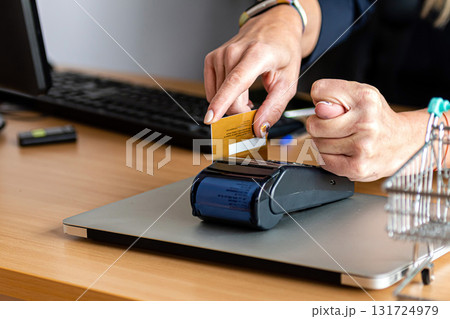a woman uses a payment card terminal to shop online and shows a fig with his other hand 131724979