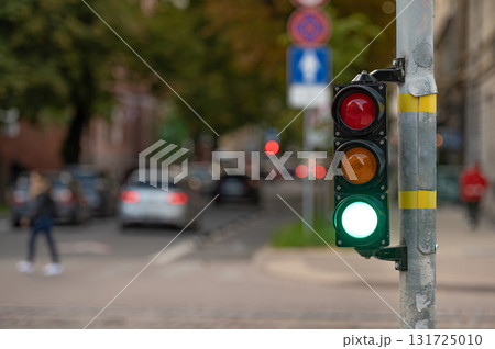 view of city traffic with traffic lights, in the foreground a semaphore with a green light, closeup 131725010