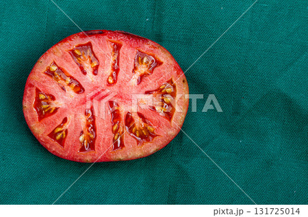 green tomato halve on a red background, closeup from above 131725014