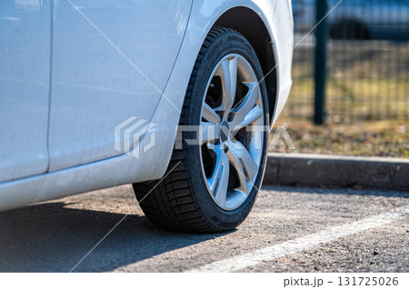 close up of the rear wheel of a white vehicle parked on the side of the street 131725026