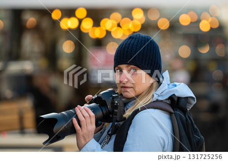 blonde middle-aged female with a camera in the evening on the city streets, lifestyle concept blonde middle-aged female with a camera in the evening on the city streets, lifestyle concept 131725256