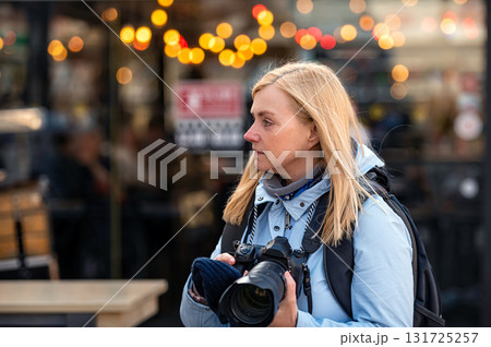 blonde middle-aged female with a camera in the evening on the city streets, lifestyle concept blonde middle-aged female with a camera in the evening on the city streets, lifestyle concept 131725257