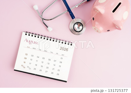 August 2026 desk calendar and stethoscope with piggy bank, Savings for health concepts. 131725377