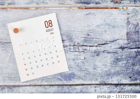 August 2026 monthly calendar and wooden push pin on blue wooden background. August 2026 monthly calendar and wooden push pin on blue wooden background. 131725500