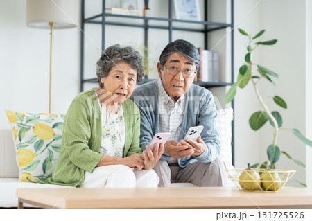 リビングでスマホを見るシニアの夫婦 リビングでスマホを見るシニアの夫婦 131725526
