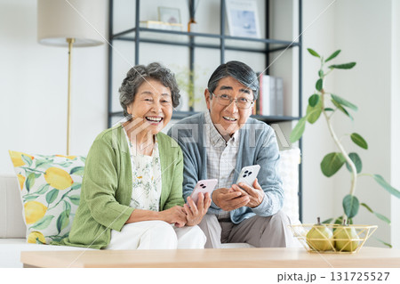 リビングでスマホを見るシニアの夫婦 リビングでスマホを見るシニアの夫婦 131725527