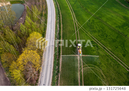 aerial view of the tractor spraying the chemicals on the large green field aerial view of the tractor spraying the chemicals on the large green field 131725648
