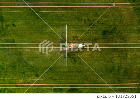 aerial view of the tractor spraying the chemicals on the large green field aerial view of the tractor spraying the chemicals on the large green field 131725651