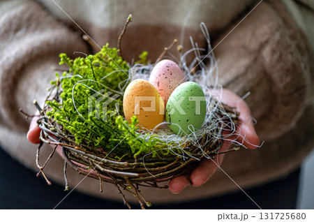 woman hands holding painted easter eggs in a small bird nest woman hands holding painted easter eggs in a small bird nest 131725680