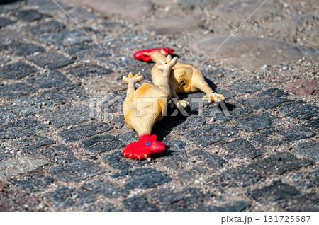 toys rubber chicken dropped on the cobblestone, close-up toys rubber chicken dropped on the cobblestone, close-up 131725687