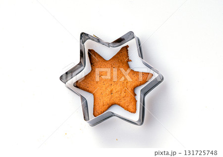 Star-shaped cookie cutter and freshly baked gingerbread, isolated, copy space, closeup Star-shaped cookie cutter and freshly baked gingerbread, isolated, copy space, closeup 131725748