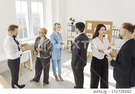 Group of confident business people talking after meeting standing in office. 131726082