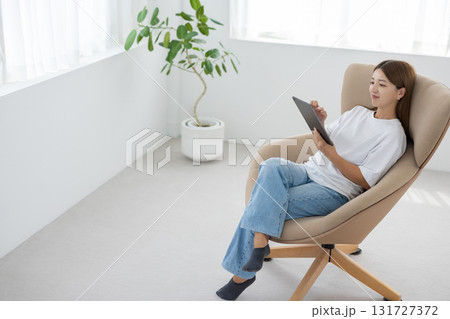 チェアに座ってタブレットを操作する若い女性 131727372