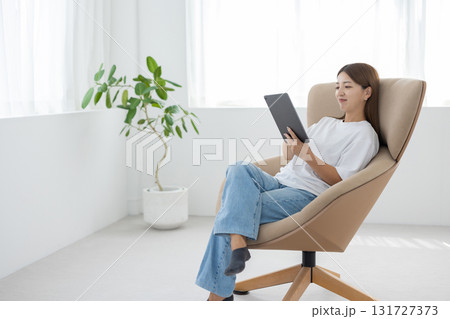 チェアに座ってタブレットを操作する若い女性 131727373