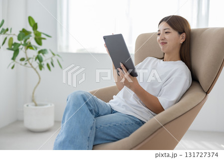 チェアに座ってタブレットを操作する若い女性 131727374