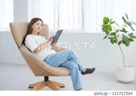 チェアに座ってタブレットを操作する若い女性 チェアに座ってタブレットを操作する若い女性 131727384