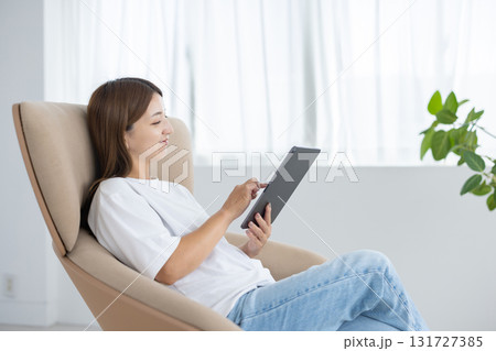 チェアに座ってタブレットを操作する若い女性 チェアに座ってタブレットを操作する若い女性 131727385