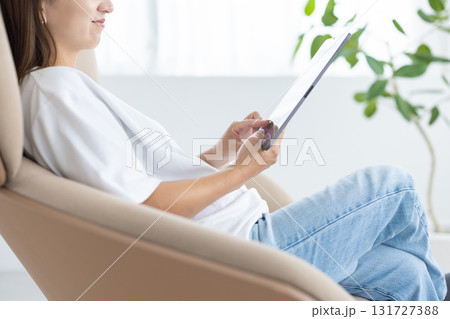 チェアに座ってタブレットを操作する若い女性 131727388
