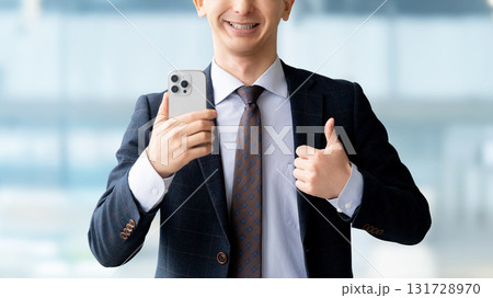 スマートフォンを持っていいね！のポーズをする男性 131728970
