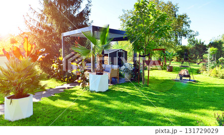Beautiful summer garden with green grass, exotic plants and aluminum pergola. Professional luxury gardening concept. 131729029
