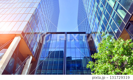 Glass office building surrounded with green trees. Eco-friendly office building. Sustainable architecture of city reducing heat carbon dioxide modern city environment. Glass office building surrounded with green trees. Eco-friendly office building. Sustainable architecture of city reducing heat carbon dioxide modern city environment. 131729319