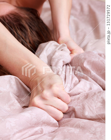 Closeup shot of hands of woman pulling the sheets in ecstasy, orgasm. 131729572