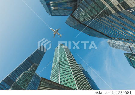 Modern glass skyscrapers on a clear day and passenger plane flies over Modern glass skyscrapers on a clear day and passenger plane flies over 131729581