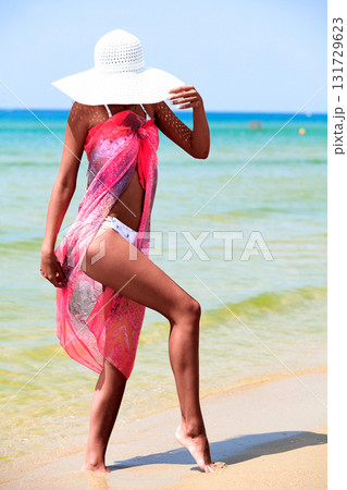 Slim tanned woman posing on a sea beach Slim tanned woman posing on a sea beach 131729623