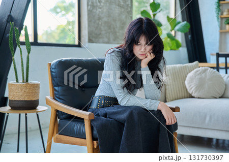 Unhappy upset tired young woman sitting on chair at home 131730397