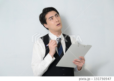 クリップボードを持って考える男性 131730547