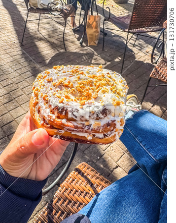 Hand Holding Sweet Pastry with Nuts and Icing 131730706