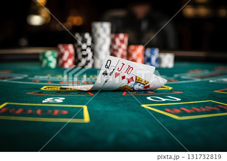 Close-up of playing cards and poker chips on green felt table, high-stakes casino game in progress with tense atmosphere 131732819