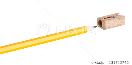 Wooden sharpener sharpening a yellow pencil on white backdrop in macro shot. Ideal for education and stationery worldwide. Wooden sharpener sharpening a yellow pencil on white backdrop in macro shot. Ideal for education and stationery worldwide. 131733746