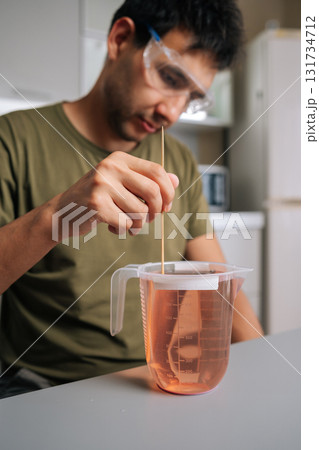 Agricultural technician wearing protective eyewear mixing chemical solution with stirrer inside sterile laboratory workspace, highlighting scientific research precision. Concept of urban farming. Agricultural technician wearing protective eyewear mixing chemical solution with stirrer inside sterile laboratory workspace, highlighting scientific research precision. Concept of urban farming. 131734712