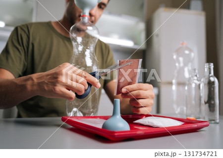 Low angle view of male farmer cutting fertilizer bag, preparing nutrients for vertical hydroponic tower garden, embodying innovative urban agriculture techniques. Concept of home gardening. 131734721