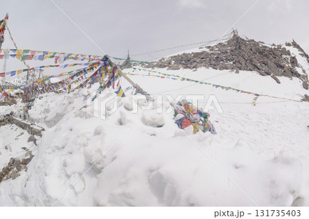 Prayer flags at a small religious site at Khardung La. This pass is located in the Ladakh mountains north of Leh and connects the Indus and Shyok river valleys and is the highest motorable road. 131735403