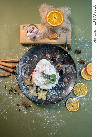 top view of meringue roll cake with mascarpone, mint and orange on black plate top view of meringue roll cake with mascarpone, mint and orange on black plate 131735519